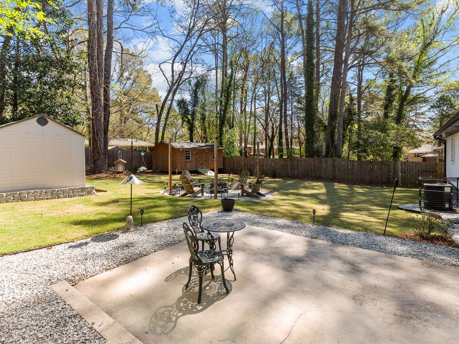 A backyard patio and lawn surrounded by tall pine trees